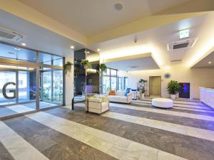 un vestíbulo de oficina con sofás, mesas y ventanas en Green Rich Hotel Okinawa Nago (Artificial hot spring Futamata Yunohana) en Nago