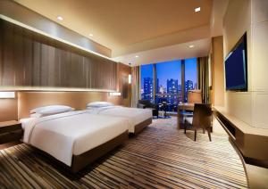 重慶市にあるHyatt Regency Chongqing Hotelのベッド2台、デスク、テレビが備わるホテルルームです。