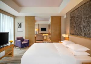 重慶市にあるHyatt Regency Chongqing Hotelの大きなベッドとリビングルームが備わるホテルルームです。