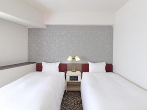 Habitación con 2 camas y mesa con lámpara. en Chisun Hotel Yokohama Isezakicho, en Yokohama