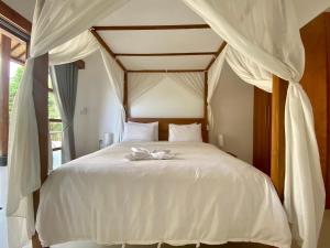 1 dormitorio con 1 cama blanca con dosel en Villa Light - Amed Bali, en Amed