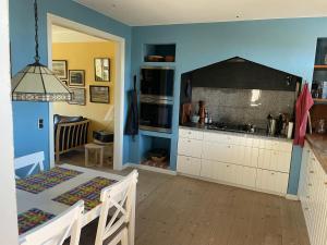 a kitchen with blue walls and a dining room with a table at Bjergly in Hjørring