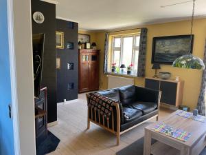 een woonkamer met een leren bank en een tafel bij Bjergly in Hjørring