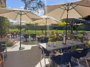 a patio with tables and chairs with umbrellas at Logis Auberge de Carolles in Carolles