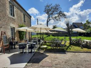 een patio met tafels, stoelen en parasols bij Logis Auberge de Carolles in Carolles