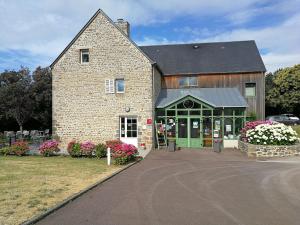 een groot bakstenen gebouw met een groene deur bij Logis Auberge de Carolles in Carolles