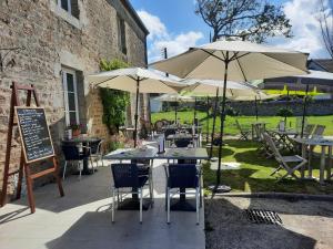 een patio met tafels en stoelen met parasols bij Logis Auberge de Carolles in Carolles