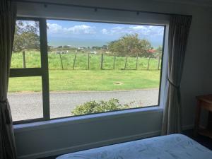 a window in a bedroom with a view of a field at Kaiaua Bayview Farm Apartment in Auckland