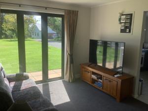 a living room with a flat screen tv and a couch at Kaiaua Bayview Farm Apartment in Auckland