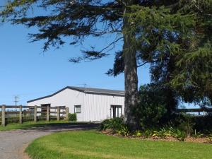 un granero blanco con un árbol en primer plano en Kaiaua Bayview Farm Apartment, en Auckland