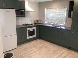 a kitchen with green cabinets and a white refrigerator at Kaiaua Bayview Farm Apartment in Auckland