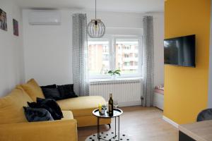 a living room with a yellow couch and a table at StudioApartman M in Valpovo