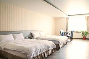 2 camas en una habitación de hotel con mesa y sillas en West Hotel Puli, en Puli