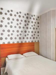 a bedroom with a white bed and a wall with hearts at Pilatus Hotel Bandung in Bandung