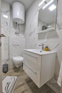 La salle de bains blanche est pourvue d'un lavabo et de toilettes. dans l'établissement Studio Pika, à Kranjska Gora