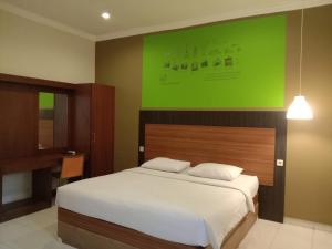 a bedroom with a large bed with a green wall at Pilatus Hotel Bandung in Bandung