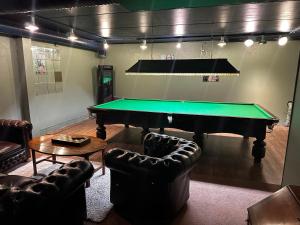 a living room with a pool table and leather chairs at Bømlo Hotell in Bømlo