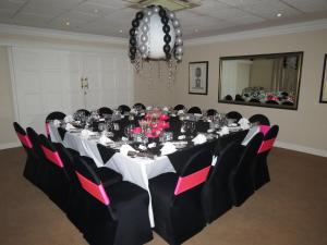 a conference room with a long table with pink and black chairs at Redlands Hotel in Pietermaritzburg
