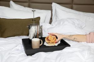 a person laying on a bed with a tray with a muffin and a drink at Bob W Oslo Sentralen in Oslo
