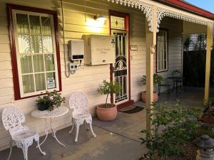 a porch of a house with two chairs and a table at Foundry Cottages in Rutherglen