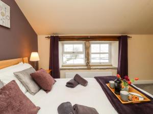 a bedroom with a bed with a tray of food on it at Mirk Cottage in Hebden Bridge