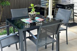 een glazen tafel met twee stoelen en een potplant bij Foundry Cottages in Rutherglen