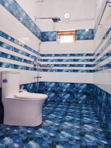 baño con aseo y azulejos azules en Marari La Rose Beach Homestay, en Mararikulam