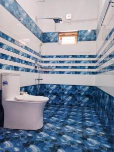a bathroom with a toilet and blue tiles at Marari La Rose Beach Homestay in Mararikulam