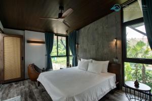a bedroom with a white bed and a ceiling fan at Oasis Spring Villa Tam Dao - Venuestay in Vĩnh Phúc +89 photos