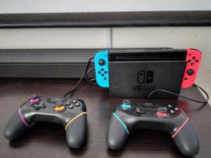 zwei Videospiel-Controller neben einem Spielesystem in der Unterkunft Cinema Resorts 3 in Motobu