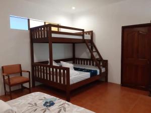 a bedroom with a bunk bed and a chair at Plantacion Isabelle in Taal