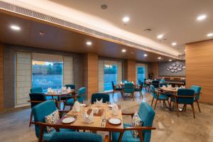 un restaurant avec des tables en bois et des chaises bleues dans l'établissement ExpoInn Suites and Convention, à Greater Noida