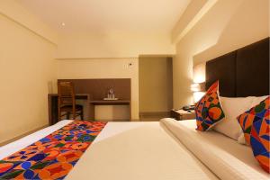 a hotel room with a bed and a table at FabHotel West Inn in Mumbai