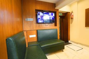 a waiting room with a green chair and a tv at FabHotel West Inn in Mumbai