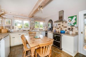 a kitchen with a wooden table and chairs at 4 Bishops Cottages in Minehead +20 photos