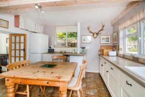 4 Bishops Cottages في مينهيد: مطبخ مع طاولة خشبية وبعض الكراسي