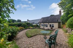 a garden with two chairs and a table in front of a house at 4 Bishops Cottages in Minehead