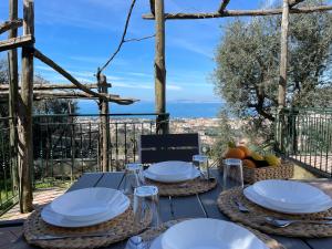 einen Holztisch mit Tellern und Weingläsern darauf in der Unterkunft SKY VIEW Villa in Piano di Sorrento