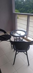 two chairs and a glass table on a balcony at RIVERSIDE PALM INN SG LEMBING in Sungai Lembing