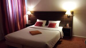 a hotel room with a large bed with red pillows at urban by balladins Perpignan in Perpignan