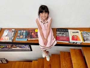 曼谷的住宿－Photohostel，坐在书架上的一个小女孩