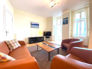 ein Wohnzimmer mit orangefarbenen Möbeln und einem Couchtisch in der Unterkunft Villa Schlossbauer - Ferienwohnung 13 in Heringsdorf