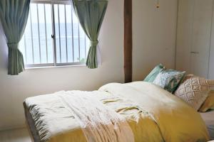 Schlafzimmer mit einem Bett und einem Fenster mit Vorhängen in der Unterkunft ニア・ヤコモ 