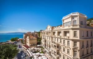 a building on a street with the ocean in the background at Hotel Bellevue - Liburnia in Opatija