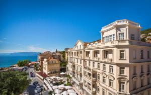 a building on a street with the ocean in the background at Hotel Palace Bellevue - Liburnia in Opatija