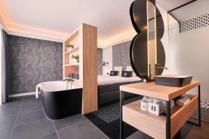 een badkamer met een bad, een wastafel en een spiegel bij Gr8 Hotel Breda in Breda