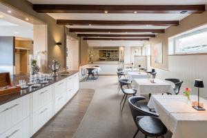 a restaurant with white tables and black chairs at Akzent Hotel Dorn in Büsum