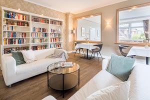 a living room with white furniture and bookshelves at Akzent Hotel Dorn in Büsum