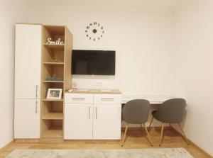Elle comprend un bureau blanc avec 2 chaises et une télévision murale. dans l'établissement Apartment SUNSET II, à Trebinje