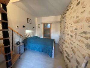 a bedroom with a bed and a stone wall at Le Buron des Loups in Soulages-Bonneval